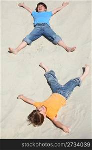 Two children lying on sand