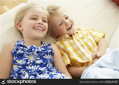 Two Children Lying Upside Down On Sofa At Home