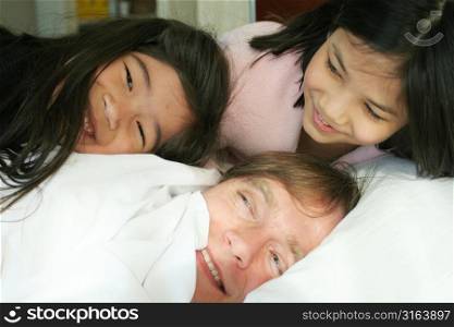 Two children lying with parent in bed