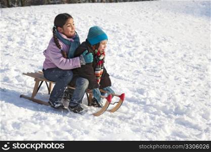 Two children on a sled having fun in the snow
