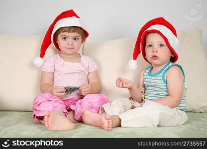 two children on sofa in santa claus hats