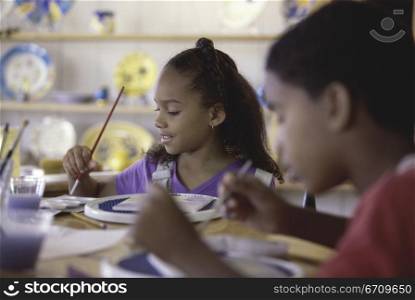 Two children painting with paintbrushes