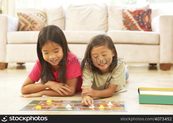 Two Children Playing Board Game At Home