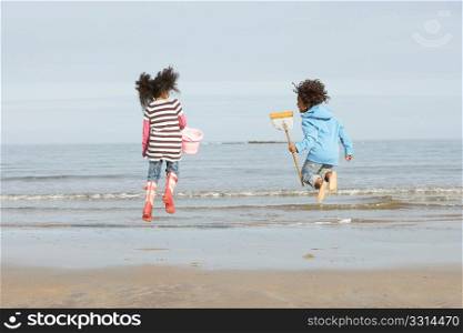 Two Children Playing By Sea On Winter Beach