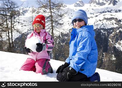 Two children playing with snow ball.