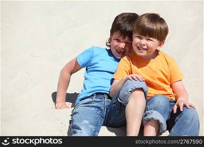 Two children sit on sand
