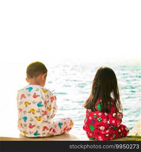 Two children sitting by the sea, morning sunshine