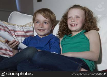 Two Children Sitting On Sofa Watching TV Together