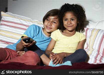 Two Children Sitting On Sofa Watching TV Together
