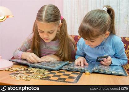Two children studying coins in album