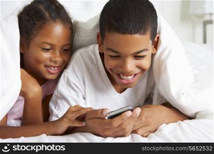 Two Children Using Mobile Phone Under Duvet