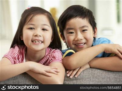 Two Chinese Children Relaxing On Sofa At Home