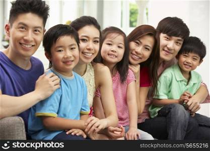 Two Chinese Families Sitting And Relaxing On Sofa Together At Home