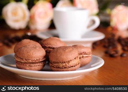 Two chocolate macaroons on wooden table with coffee background