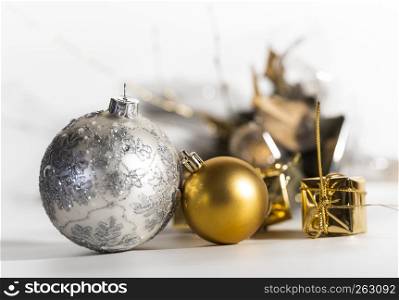 Two Christmas balls and a few little gifts with a white background, golden and silver chistmas balls out of glass, one with ornaments