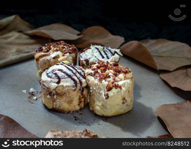 Two Cinnabon Chocobon  Soft Chocolate Buns  topped with rich cream cheese frosting and Two Caramel Pecanbon topped with decadent caramel frosting and pecans on ceramic tray. The concept of delicious food, Copy space, Selective Focus.
