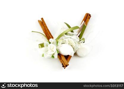Two cinnamon sticks decorated with bonbons and ribbon isolated on white. Wedding gift.