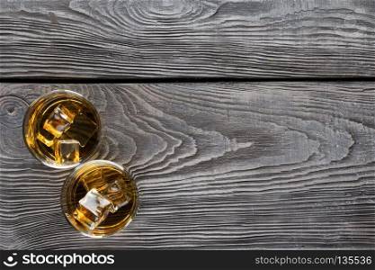 Two circular glass of whiskey with ice on wooden background. Two circular glass of whiskey with ice