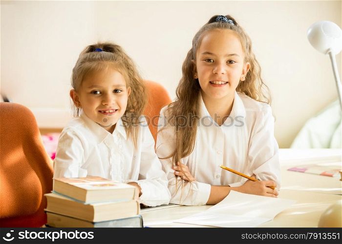 Two classmates sitting at desk and smiling at camera