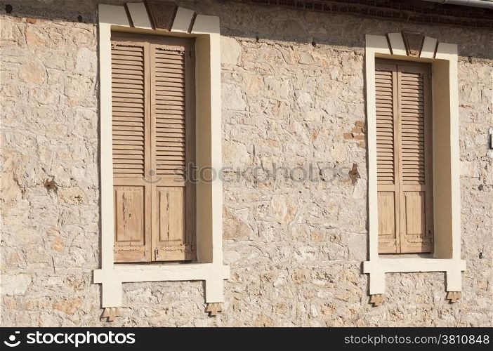 Two closed wooden windows on stone house wall