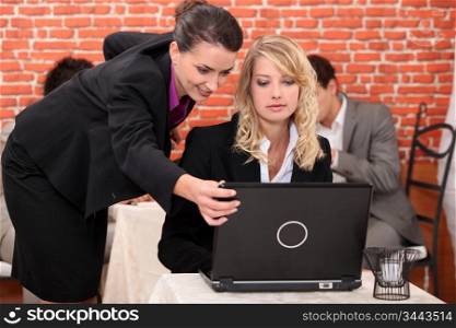 Two co-worker in restaurant looking at laptop screen