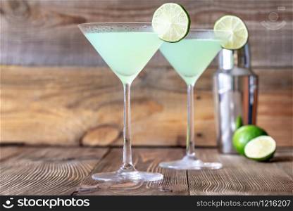 Two cocktail glasses of classic daiquiri on the wooden background