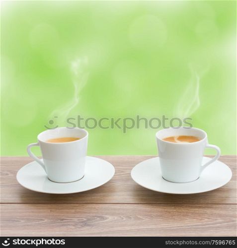 two coffee cups in garden on wooden table. two coffee cups