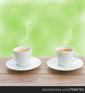 two coffee cups in garden on wooden table. two coffee cups