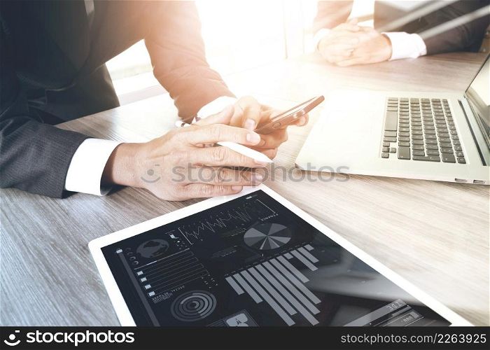 two colleagues businessman discussing data and digital tablet and computer laptop with smart phone with digital business strategy on wooden desk as concept