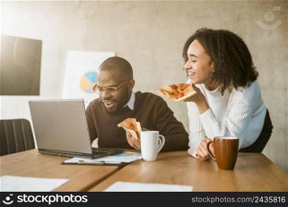 two colleagues having pizza during office meeting break