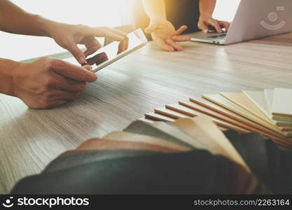 two colleagues interior designers discussing data with blank screen new modern computer laptop and pro digital tablet with sample material on wooden desk as concept