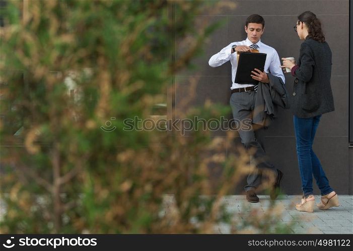 Two colleagues standing outdoors near office building and talking