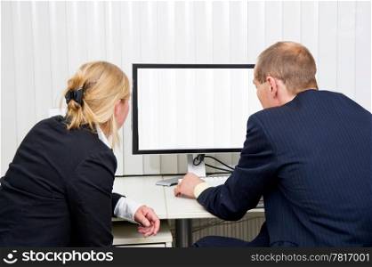 Two colleagues staring at a monitor with blinds in a blinded office
