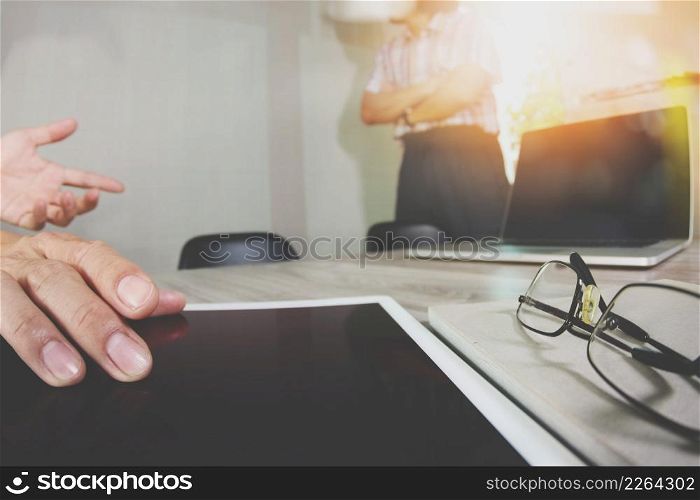 two colleagues web designer discussing data and blank screen digital tablet and computer laptop with smart phone on wooden desk as concept