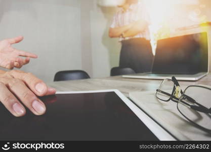 two colleagues web designer discussing data and blank screen digital tablet and computer laptop with smart phone on wooden desk as concept