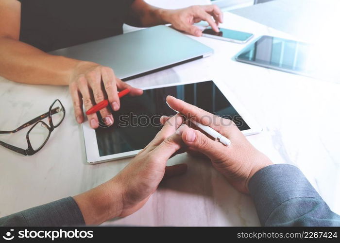 two colleagues website designer discussing data and digital tablet and computer laptop and smart phone on marble desk as concept, sun flare effect