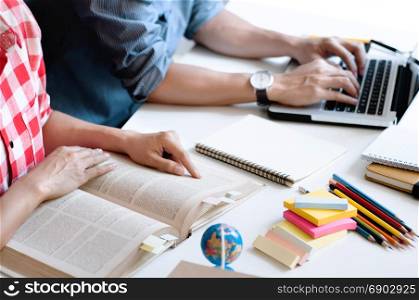 Two college students reading a book or doing homework together at a class or home