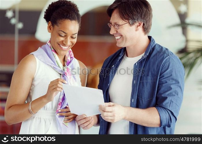 Two collegues standing and discussing papers in a office