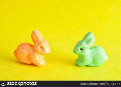 Two colorful bunnies used for decoration over the easter period isolated on a yellow background
