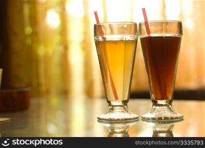 Two colorful fruit beverages on glass table in coffee shop.