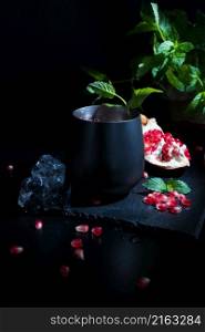 two colorful summer drinks with pomegranate and mint on a black table