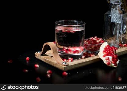 two colorful summer drinks with pomegranate and mint on a black table