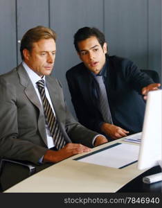 Two concentrated businessmen working together on a laptop in the office