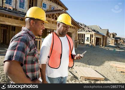 Two construction workers using mobile phone on construction site