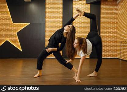 Two contemporary dance performers poses in studio. Female dancers training in class, modern grace dancing, stretching exercise. Two contemporary dance performers poses in studio