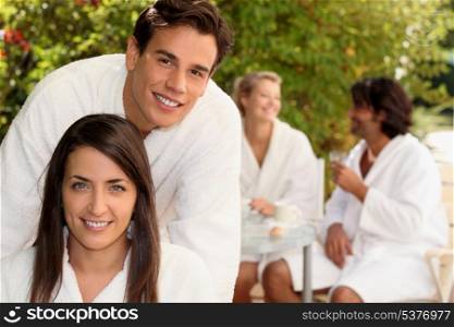 Two couple sat in garden wearing dressing gowns