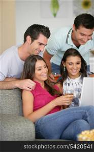 Two couples at home laughing at a laptop