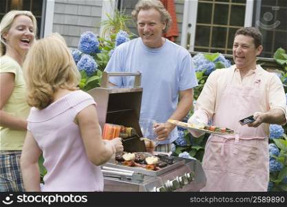 Two couples cooking food in an oven and smiling