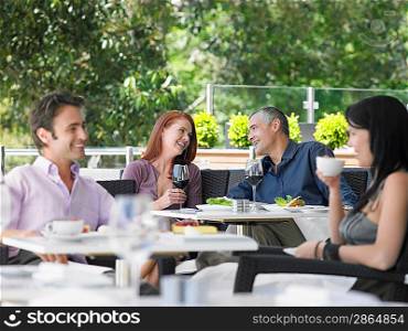 Two couples drinking at outdoor cafe focus on far couple
