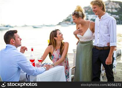 Two couples greeting at waterfront restaurant, Majorca, Spain